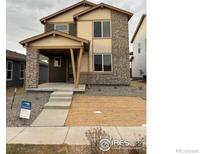 Two-story house with stone and beige siding, welcoming porch, and landscaped yard at 2778 Optimista Pl, Brighton, CO 80601