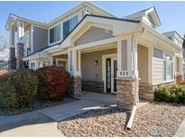 Beige two-story home with stone accents and a covered entryway at 13708 Legend Trl # 101, Broomfield, CO 80023