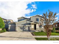 Two-story house with gray siding, stone accents, and a three-car garage at 2901 Quartz Pl, Frederick, CO 80516