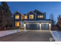 Two-story house with a gray exterior, two-car garage, and snowy front yard at 767 Pope Dr, Erie, CO 80516