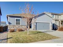 Attractive two-story home with gray siding, stone accents, and a two-car garage at 14817 Longhorn Dr, Mead, CO 80542