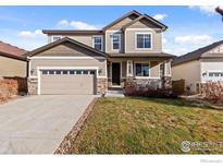 Two-story house with beige siding, stone accents, and a two-car garage at 6512 Empire Ave, Frederick, CO 80516