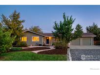 Ranch home with mature landscaping, a large driveway, and a three-car garage at 9938 Plateau Rd, Longmont, CO 80504