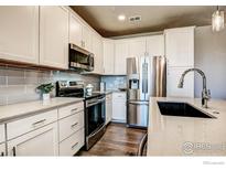 White cabinets, stainless steel appliances, and quartz countertops in kitchen at 410 High Point Dr # 105, Longmont, CO 80504