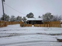 Snow-covered house exterior with fenced yard at 11488 County Road 20, Fort Lupton, CO 80621