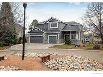 Two-story house with gray siding, stone accents, and a three-car garage, viewed from across the street at 1366 Teton Pt, Lafayette, CO 80026