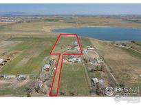 Aerial view of expansive property with a home and outbuildings near a lake at 524 E County Road 8, Berthoud, CO 80513