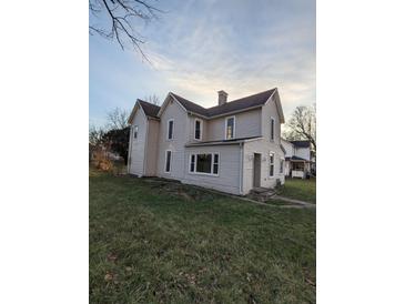 Two-story house with light beige siding, a large yard, and mature trees at 213 E Broadway St, Alexandria, IN 46001