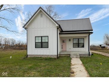 Charming white farmhouse exterior with pink door and gray metal roof at 706 S Main St, Whitestown, IN 46075