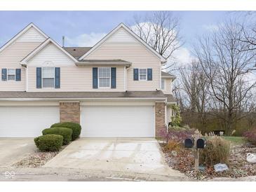 Two-story townhouse with neutral siding, attached garage, and landscaping at 9369 Eden Woods Ct, Indianapolis, IN 46260