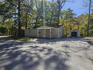 Tan house with small front porch, gravel driveway, and storage shed at 184 Lake Hart, Mooresville, IN 46158