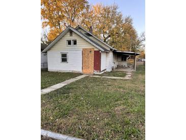 White house with a red door and yard needs some repairs at 1656 Nelson Ave, Indianapolis, IN 46203