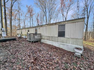 Single-wide manufactured home with wooden deck and surrounding trees at 4355 E Streacher Rd, Bloomington, IN 47408