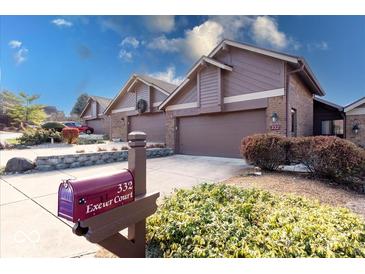 Exterior view of charming townhouses with attached garages and well-manicured landscaping at 332 Exeter Ct, Greenwood, IN 46143