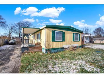 Tan mobile home with green trim, covered porch, and small yard at 33 Miami Dr, Noblesville, IN 46062