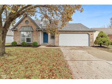 Brick house with a blue door, attached garage, and landscaping at 7548 Crickwood Ln, Indianapolis, IN 46268