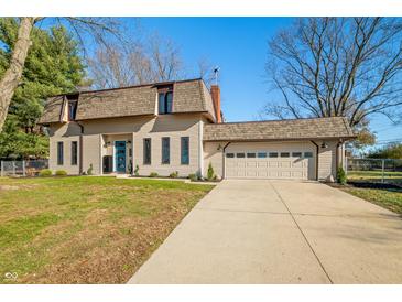 Beige house with brown roof, attached garage, and landscaped lawn at 3235 Beechnut Ct, Columbus, IN 47203