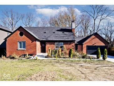 Brick house with a gray roof, black garage door, and landscaping at 4127 N Sherman Dr, Indianapolis, IN 46226