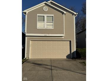 Tan two-story house with a beige garage door and a small front yard at 5283 Tufton Dr, Indianapolis, IN 46254