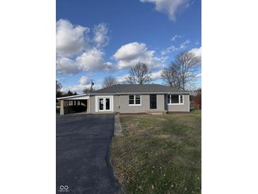 Newly renovated ranch home featuring a gray brick exterior, landscaped lawn, and attached carport at 3118 26Th St, Columbus, IN 47203