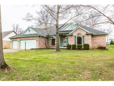 Charming brick home with green trim, a two-car garage, and a landscaped front yard at 121 Derbyshire Dr, Indianapolis, IN 46229