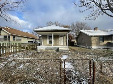 One-story home with a small front porch and a fenced yard dusted with snow at 1827 Mansfield St, Indianapolis, IN 46202