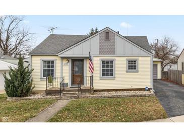 Charming yellow house with gray accents, American flag, and landscaping at 5338 E 20Th St, Indianapolis, IN 46218