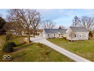 Gray farmhouse with detached garage, long gravel driveway, and mature trees on a spacious lot at 7860 E 400 S, Columbus, IN 47203