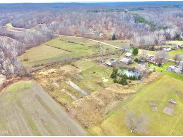 Aerial view showing a large property with farmlands, a pond, and multiple buildings at 7021 Bellsville Pike, Columbus, IN 47201