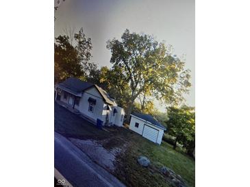 House with detached garage and large trees in the front yard at 7739 Mooresville Rd, Indianapolis, IN 46183