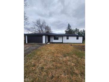 White brick ranch house with black accents, a dark garage door, and a spacious yard at 6805 E County Road 100 S, Avon, IN 46123