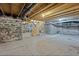 Unfinished basement with exposed stone walls and a wooden staircase at 412 W 11Th St, Anderson, IN 46016