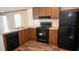 Modern kitchen with dark wood cabinets, black appliances, and granite countertops at 31 Blue Water Dr, Cicero, IN 46034