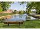 Serene pond with a wooden bench, surrounded by lush greenery and brick buildings at 8751 Jaffa Court E Dr # 35, Indianapolis, IN 46260