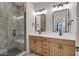 Double vanity bathroom with marble shower, modern lighting, and wood cabinets at 671 E 16Th St, Indianapolis, IN 46202
