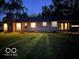 Evening view of a ranch-style home with lighted windows and a lush lawn at 1231 E 88Th St, Indianapolis, IN 46240