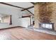 Spacious living room featuring hardwood floors, a stone fireplace, and exposed wooden beams at 9996 N County Road 200 W, Muncie, IN 47302