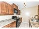 Bright kitchen with dark wood cabinets, granite countertops, and black appliances at 2719 E 28Th St, Indianapolis, IN 46218
