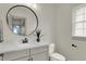 Simple bathroom with a vanity, toilet, and large round mirror at 220 Sanders St, Indianapolis, IN 46225