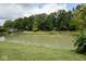 Picturesque pond surrounded by trees and a small cottage at 9100 S Us Highway 35, Muncie, IN 47302