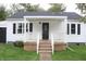 White house with a covered porch, black door, and well-manicured lawn at 2312 E 22Nd St, Muncie, IN 47302