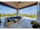 Relaxing covered patio with sectional sofa and outdoor dining area, overlooking a pool and landscaped yard at 9760 Windy Hills Dr, Zionsville, IN 46077