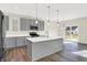 Open kitchen with gray cabinets, large island, stainless steel appliances, and hardwood floors at 19663 Atwater Ave, Sheridan, IN 46069