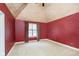 Spacious bedroom with red walls, carpeted floors, and a large window with plaid curtains at 8358 Hidden Point Dr, Indianapolis, IN 46256
