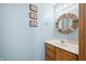 Small bathroom with wood vanity, single sink, and decorative mirror at 1936 Broadmoor Ln, Columbus, IN 47203