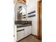 Small bathroom with a vanity, sink, arched mirror, and floating shelves at 735 Lexington Ave # Apt 8, Indianapolis, IN 46203