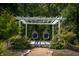 White wooden pergola with hanging chairs and lush landscaping at 12980 W Mt. Healthy Rd, Columbus, IN 47201
