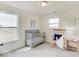 Bright Bedroom featuring a crib, rocking chair, and large window at 3923 Windstar Way, Columbus, IN 47203