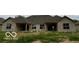 Tan brick home with gray roof, covered patio, and backyard at 980 Paris Dr, Franklin, IN 46131