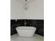 Bathroom with free-standing tub, black marble tile, and chandelier at 525 Schmitt Rd, Indianapolis, IN 46239